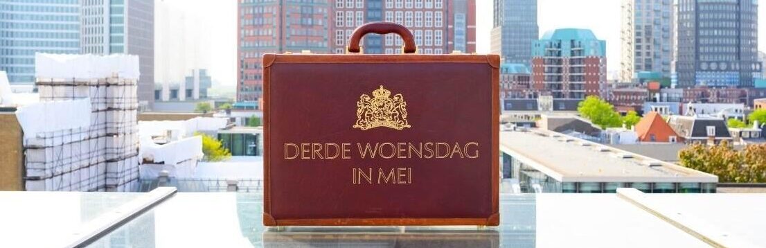koffertje met de tekst erop: 'derde woensdag in mei'. Op de achtergrond hoge gebouwen.